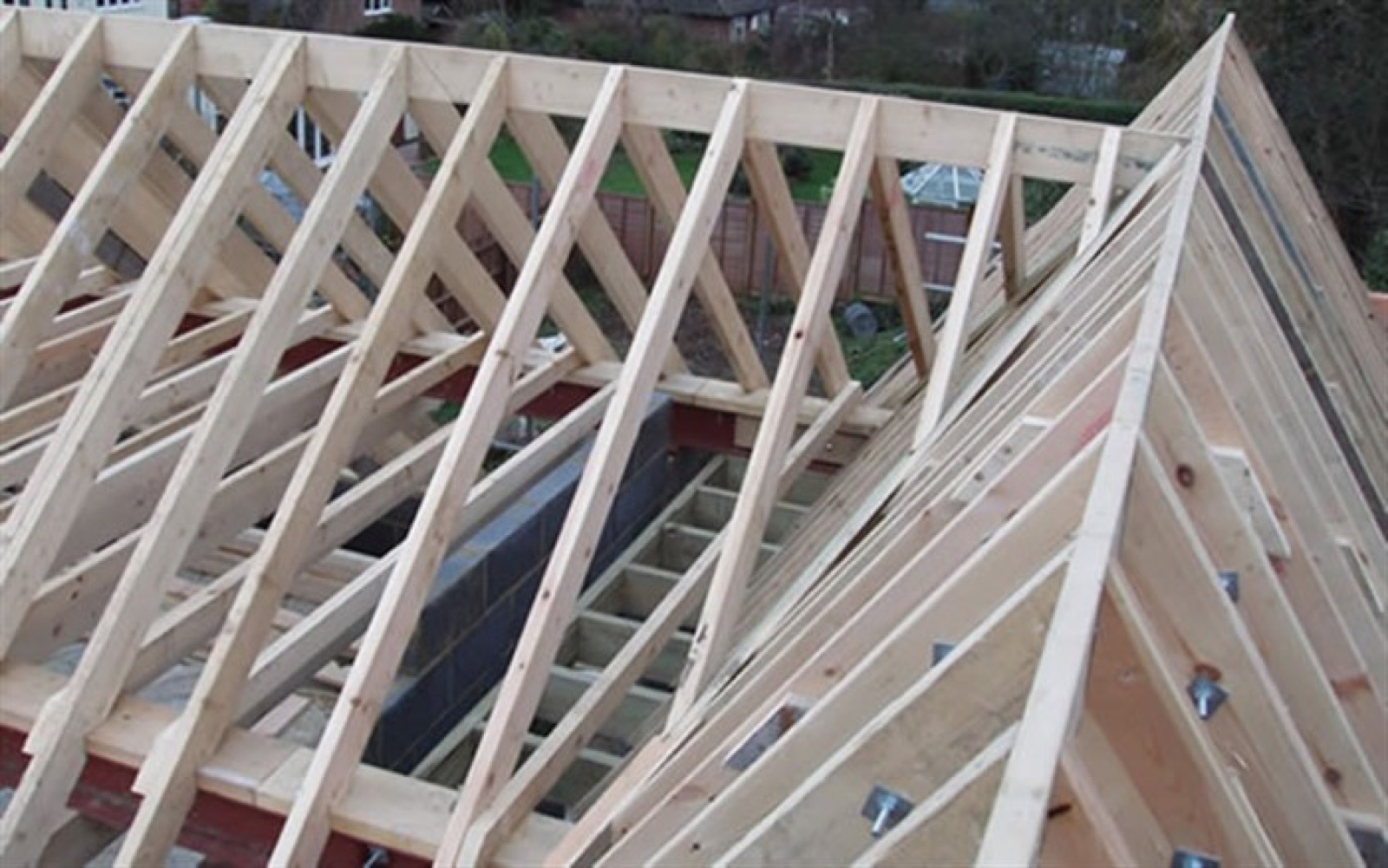 Custom pitched stick roof structure being framed on a residential build