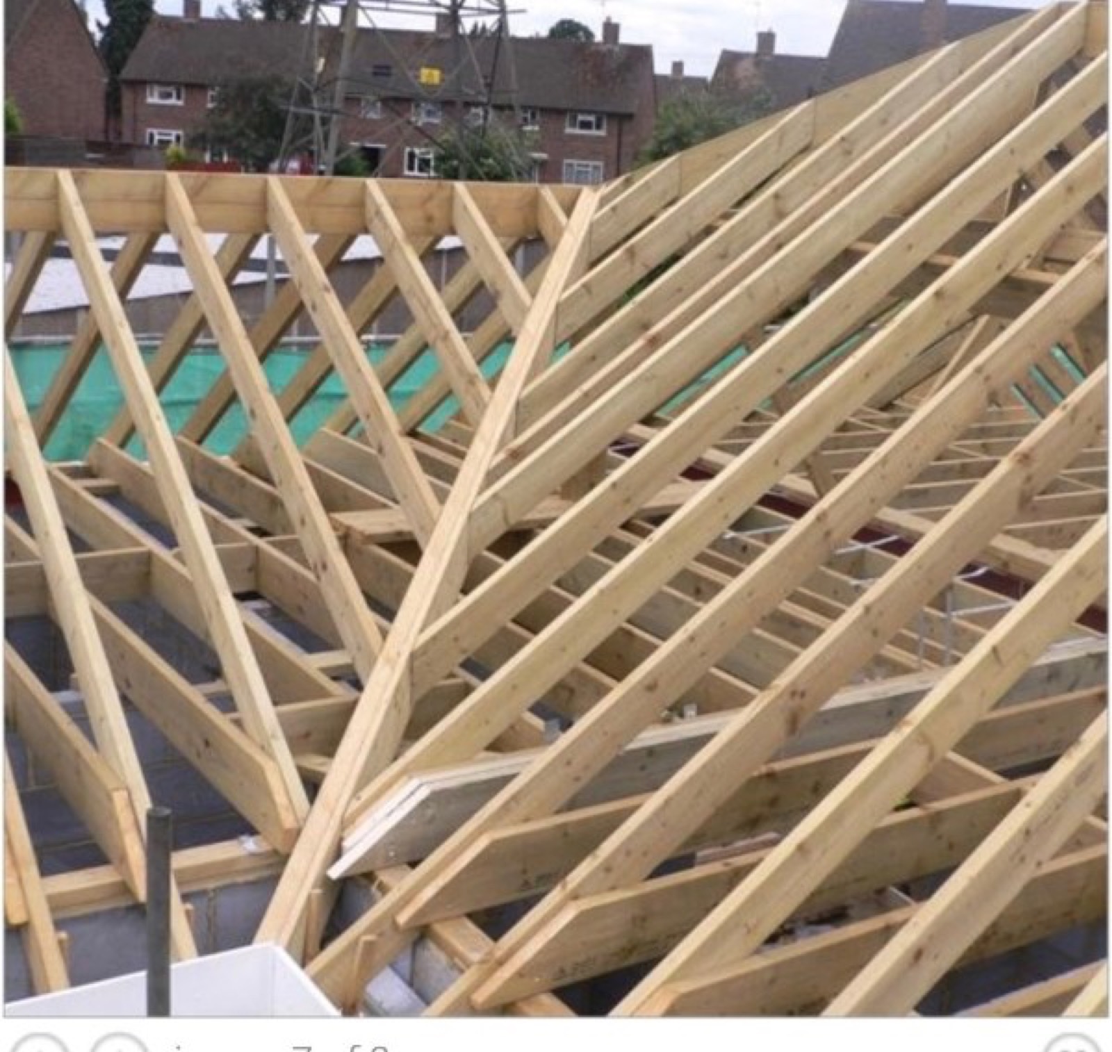 Complex stick frame roof under construction with intersecting timber members and angled rafters