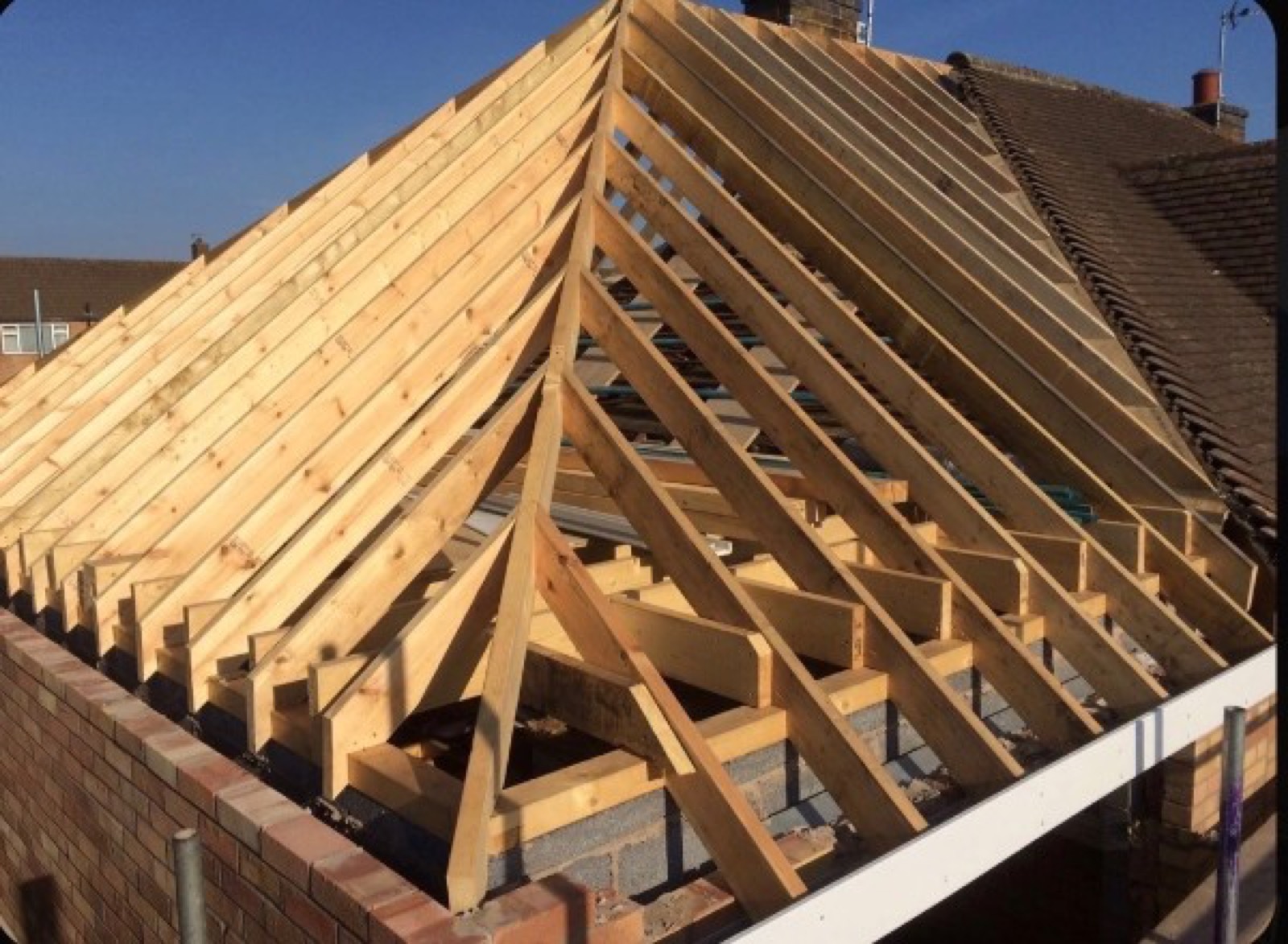 Residential stick roof framing on a house extension with timber rafters and roof structure in place